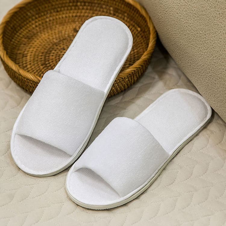 Terry open-toe hotel slippers near rattan basket